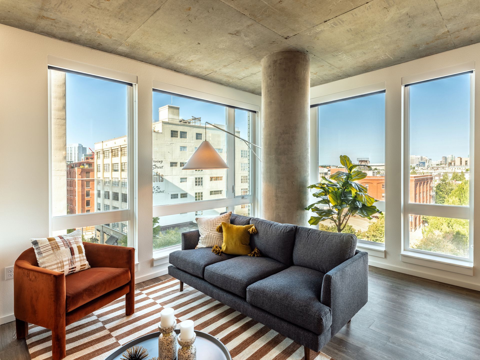 A living room with a couch , chair , coffee table and lots of windows.