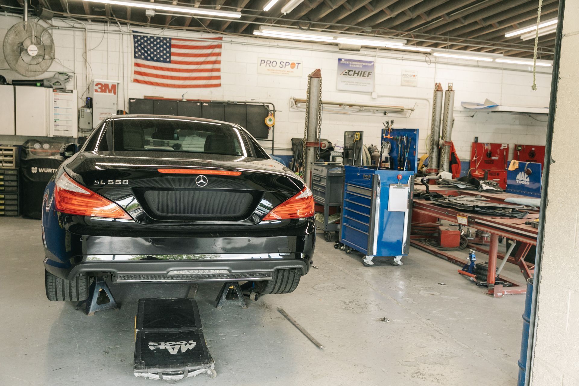Auto repair shop with a car lift, tool cabinets, and a vehicle on the right side