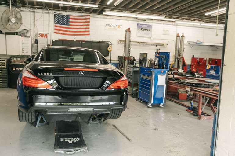 Auto repair shop with a car lift, tool cabinets, and a vehicle on the right side