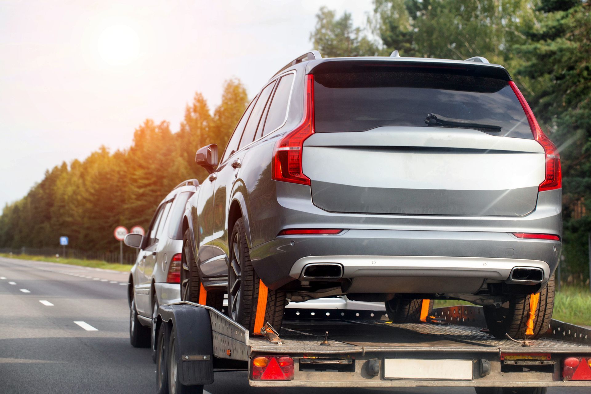 SUV being towed on a flatbed truck, traveling on a highway.