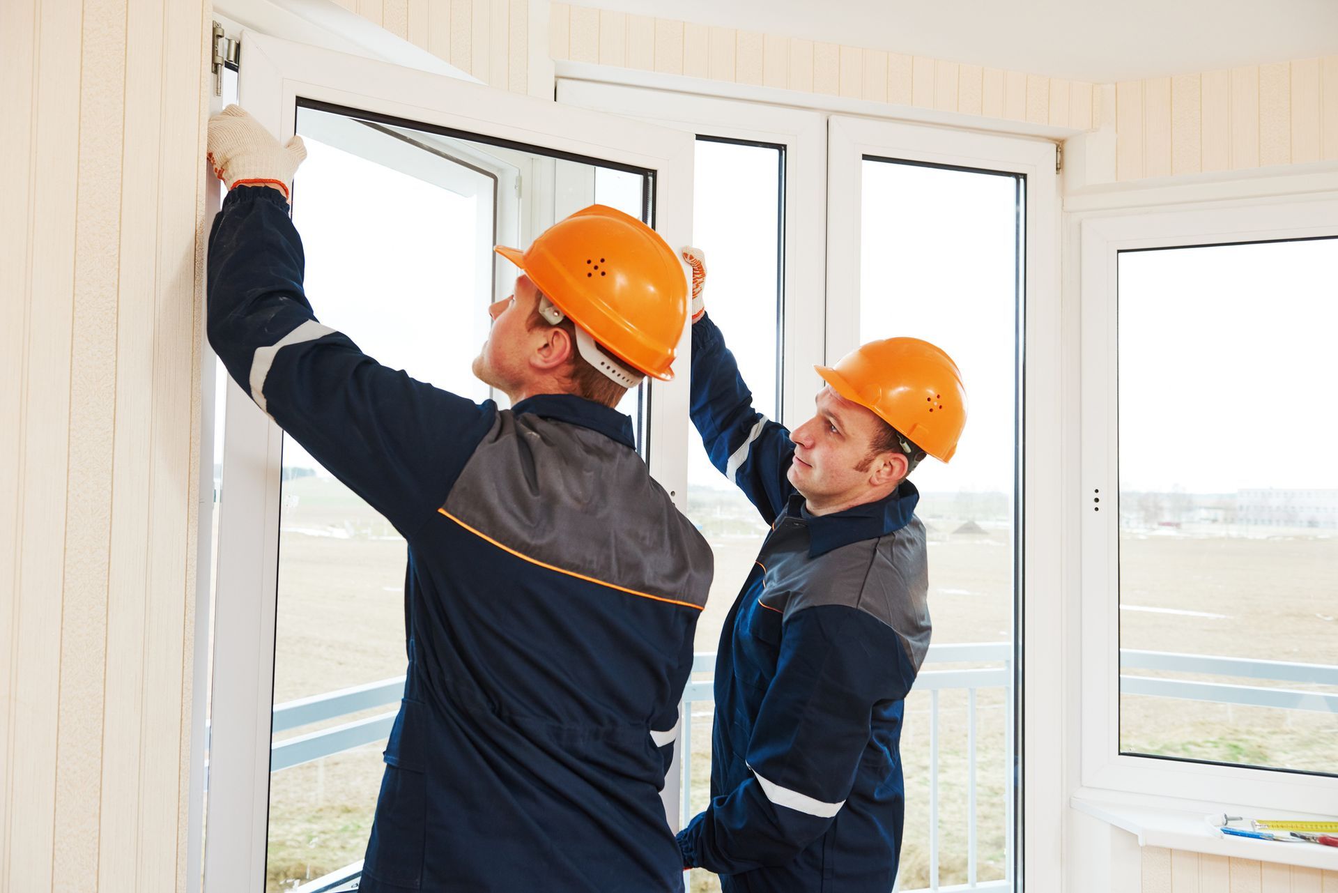 Two men in hard hats installing a window in Cincinnati, OH, representing B & B Window & Door's expert window installation services.  