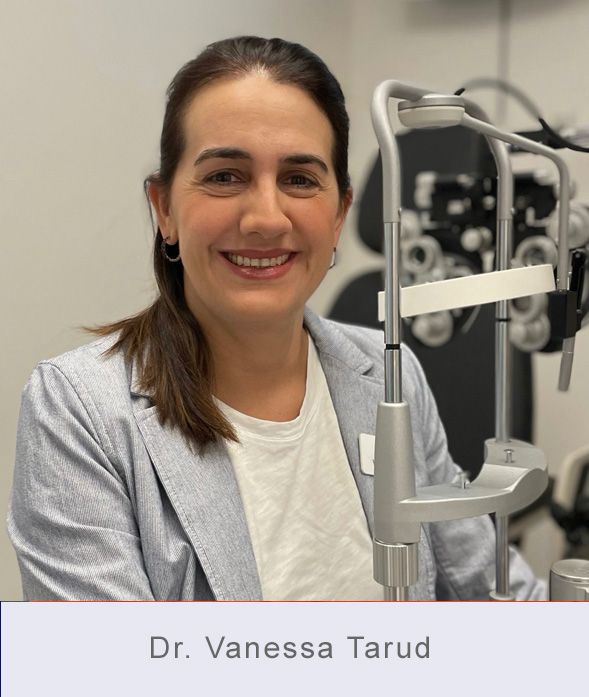 Dr. Vanessa Tarud smiles in an eye exam room, next to an eye examination machine.