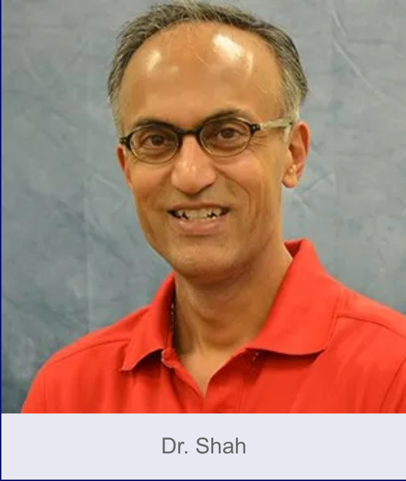Dr. Shah wearing glasses and a red shirt, smiling.