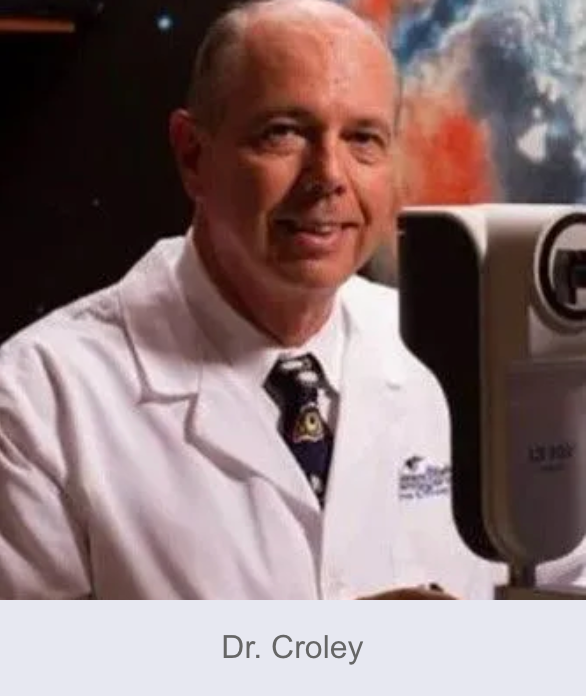 Dr. Croley in a white lab coat, smiling, near a medical device, with a blurred background.