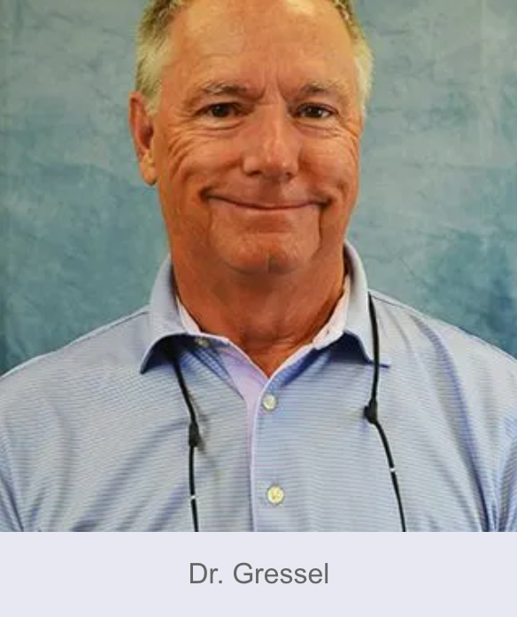 Dr. Gressel, a man with glasses, smiles, wearing a light blue collared shirt, in front of a blue background.