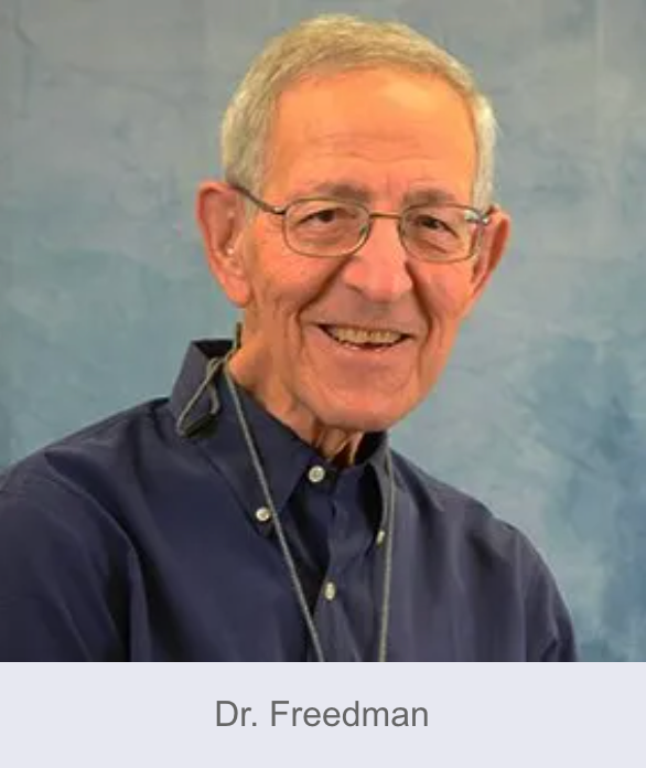 Dr. Freedman, smiling, wearing glasses and a blue shirt, stands against a blue background.
