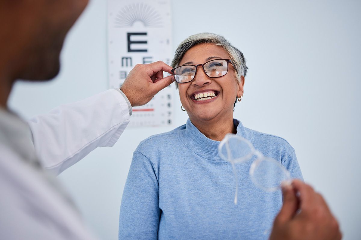 Optometrist adjusting eyeglasses on patient during eye exam.