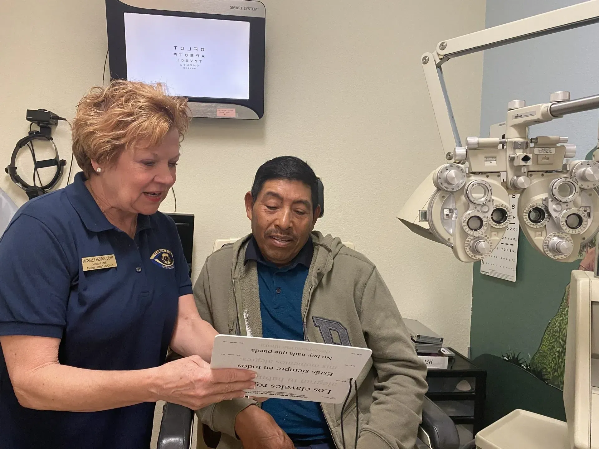Optometrist showing a patient paperwork; exam room setting with eye exam equipment.