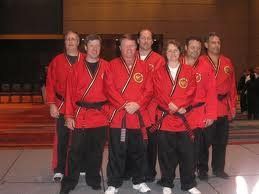 A group of people in red karate uniforms are posing for a picture.