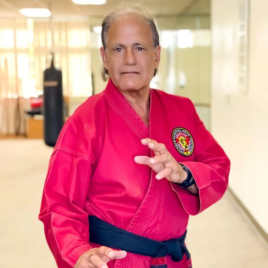 A man in a red karate uniform is standing in a hallway.