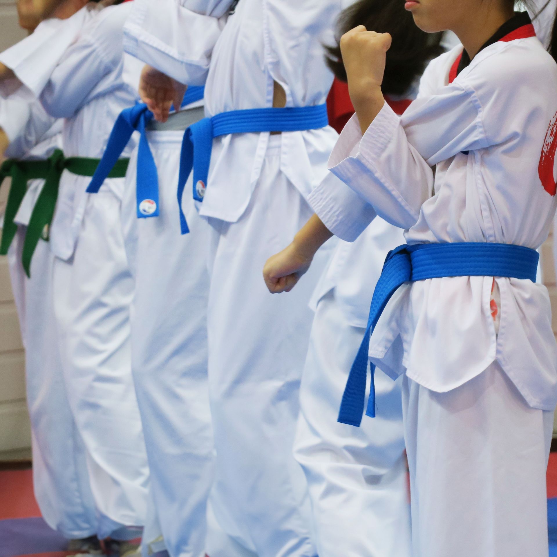 A group of people wearing white karate uniforms with blue belts