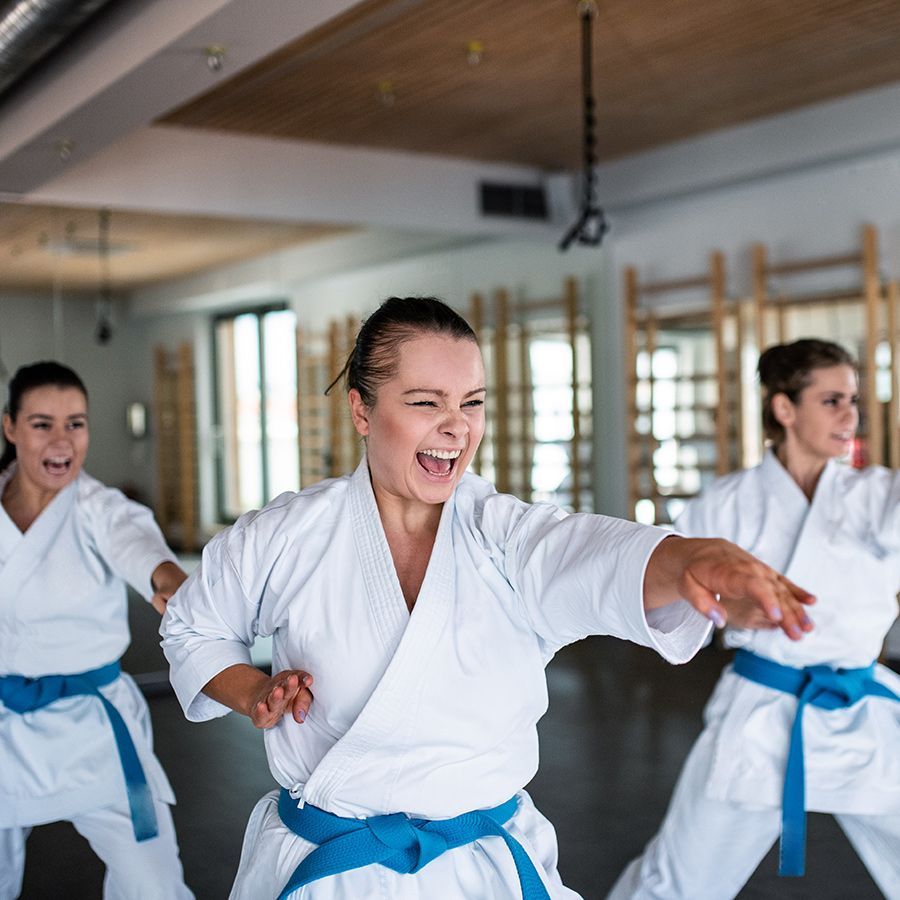 A group of women are practicing karate in a gym.