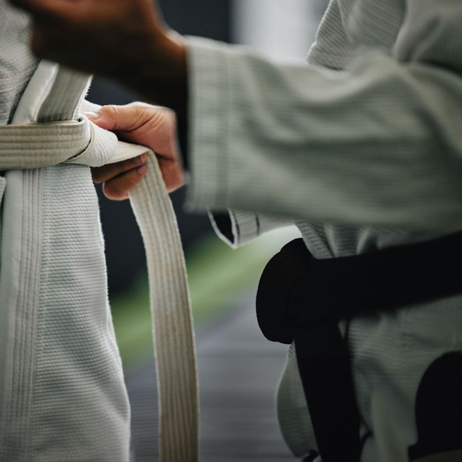 A person is tying a white belt around another person 's waist