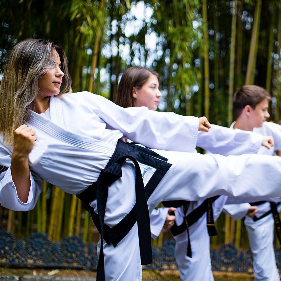 A group of people are practicing karate in a forest.