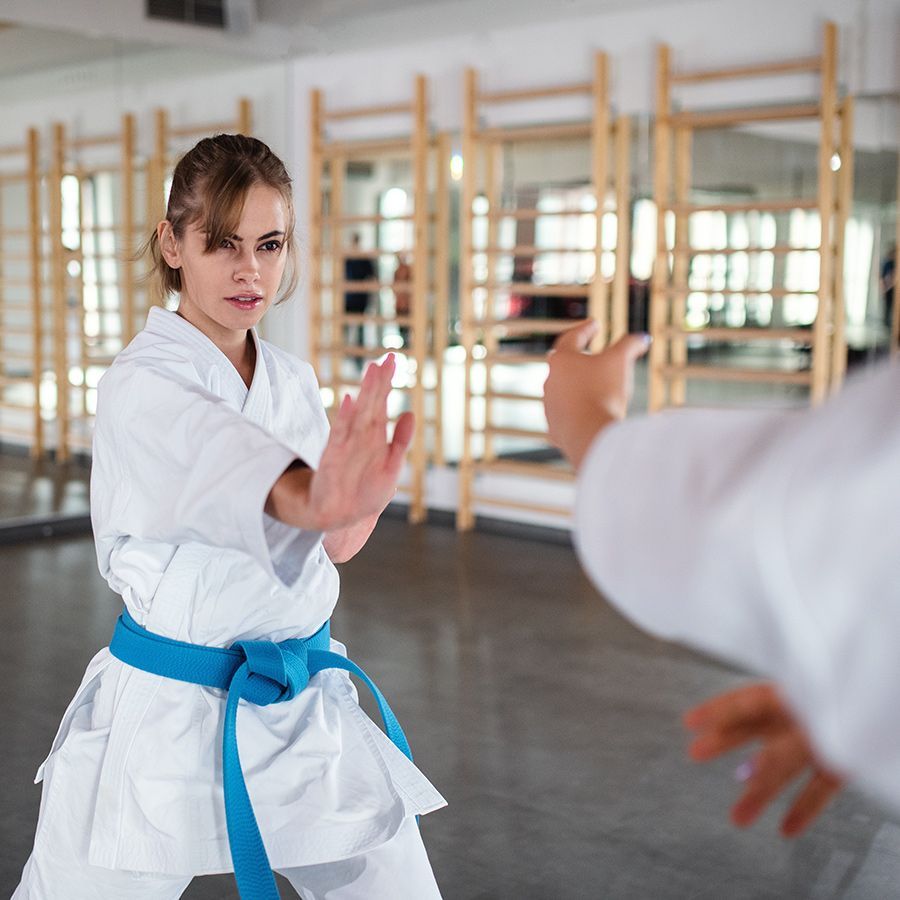 A woman in a white karate uniform with a blue belt
