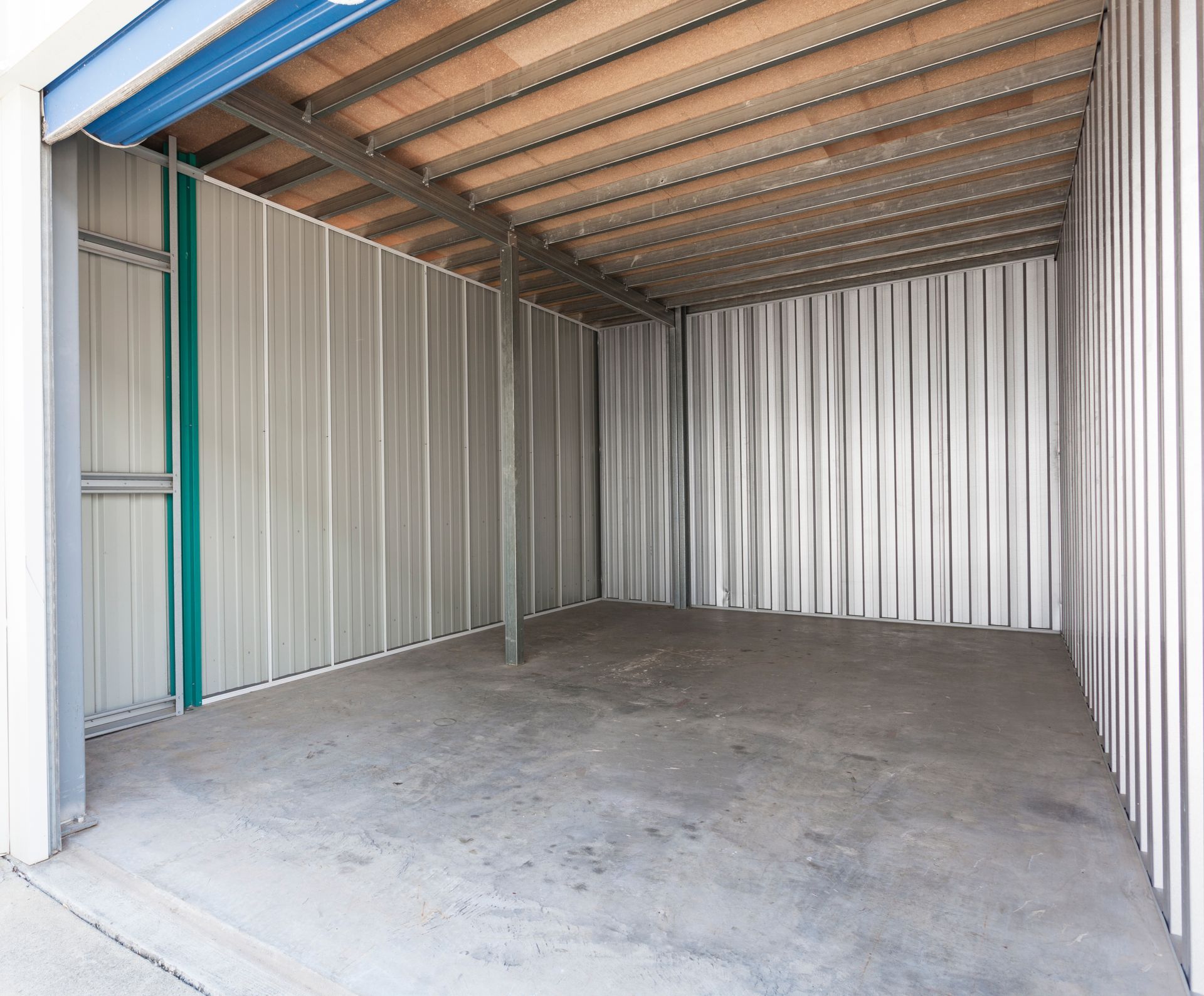 An empty garage with a blue door and a wooden ceiling