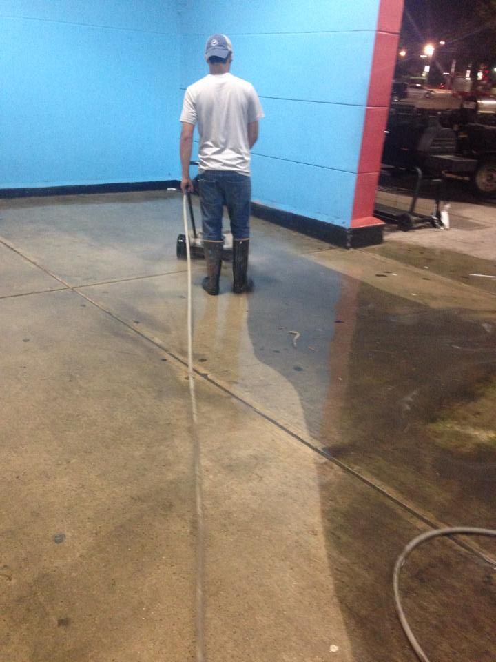 A man is cleaning the floor of a building with a broom.