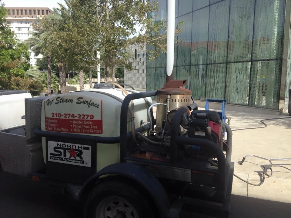 A trailer with a machine on it is parked in front of a building.