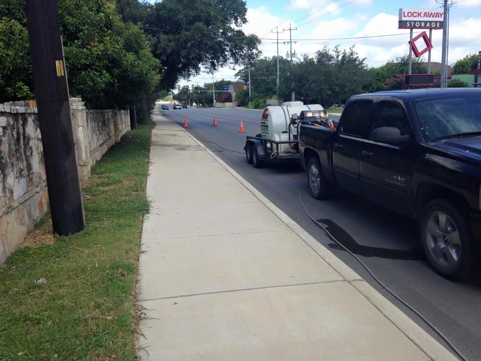 A black truck with a trailer attached to it is parked on the side of the road