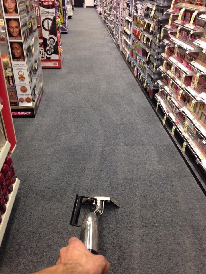A person is cleaning the floor of a store with a vacuum cleaner