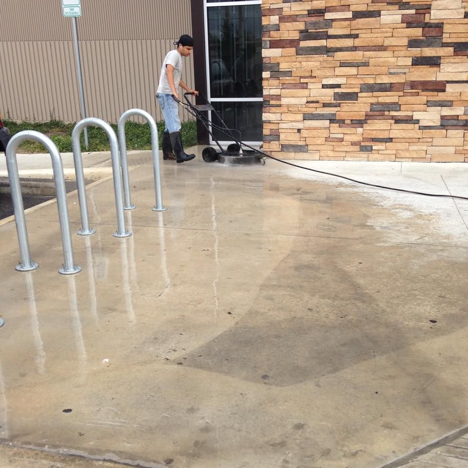 A man is using a machine to clean the concrete outside of a building