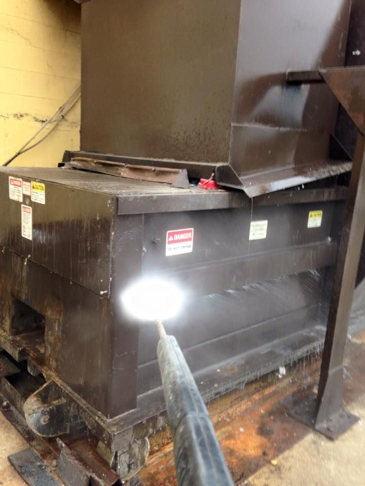 A large black dumpster is sitting on a wooden floor.