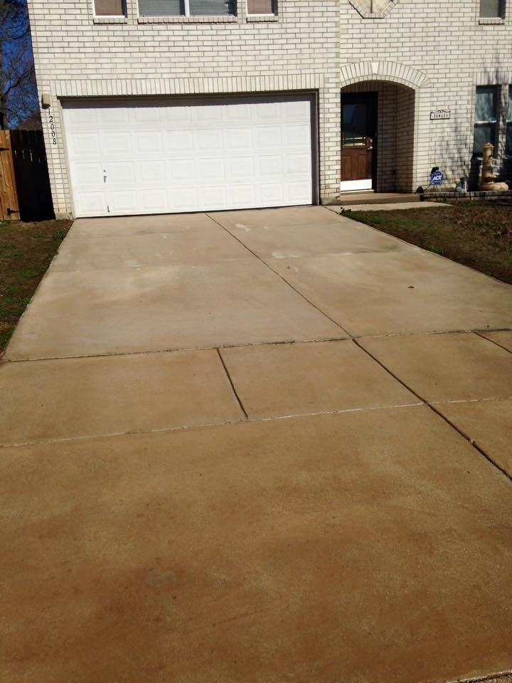 A driveway leading to a white brick house with a white garage door