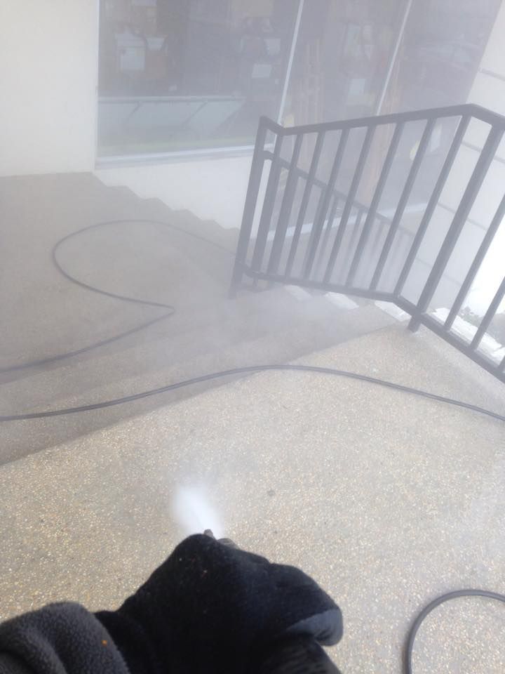 A person is standing in front of a staircase with a hose coming out of it.