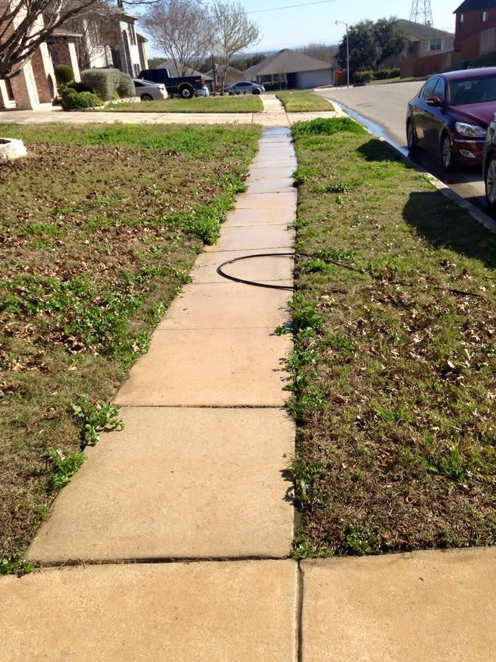 A sidewalk in a residential neighborhood with a car parked on the side of it