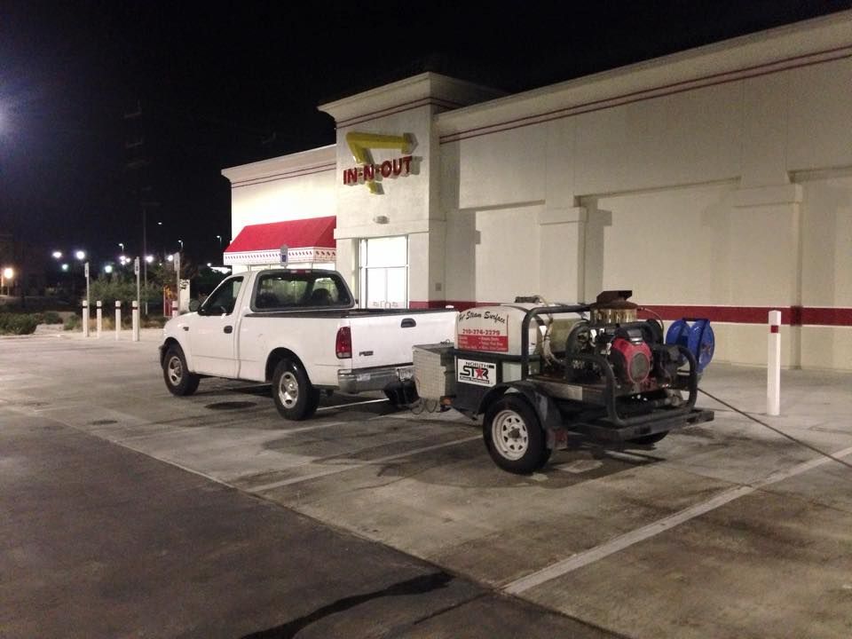 A white truck is parked in front of an in-n-out restaurant