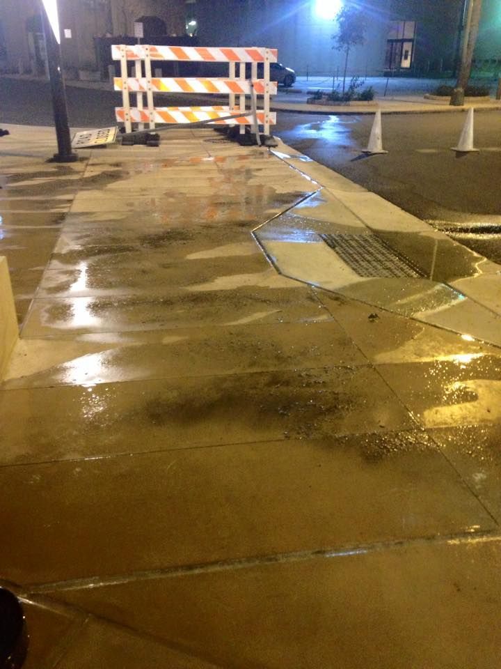 A wet sidewalk with a barrier in the middle of it