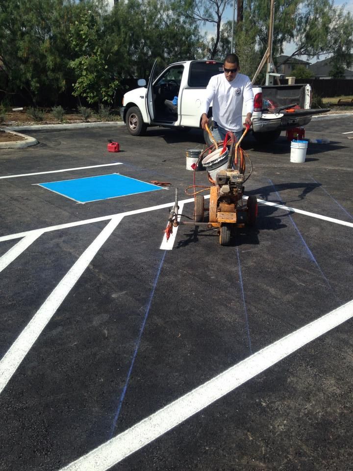 A man is using a machine to paint a parking lot