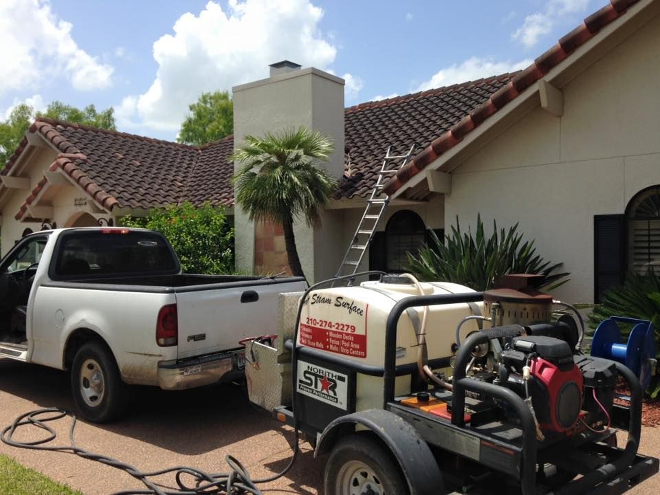 A white truck is parked in front of a house with a trailer attached to it.