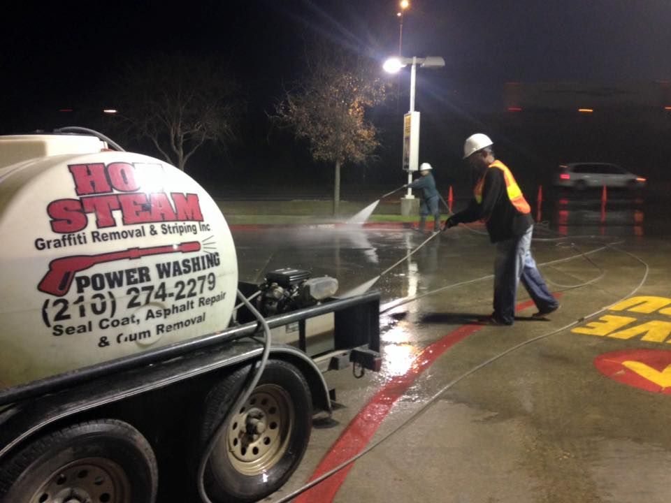A man is cleaning a parking lot with a high pressure washer.