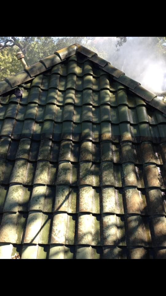 A close up of a roof with green tiles and trees in the background.