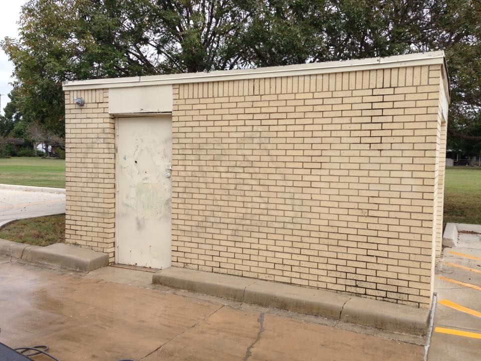 A brick building with a white door in a parking lot