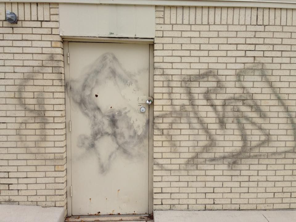 A white door on a brick wall with graffiti on it