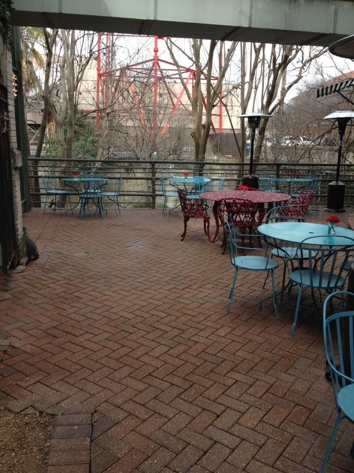 A patio with tables and chairs and a ferris wheel in the background
