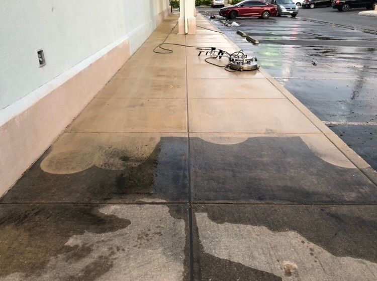 Sidewalk being pressure washed, showing before/after comparison; machine in use.