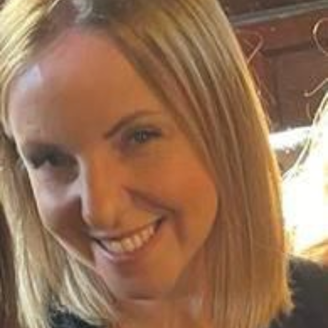 Woman with blonde hair smiling, looking at the camera.