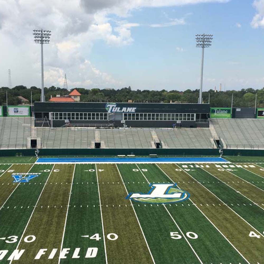 Football field with Tulane logo, stadium seating, and blue endzone.