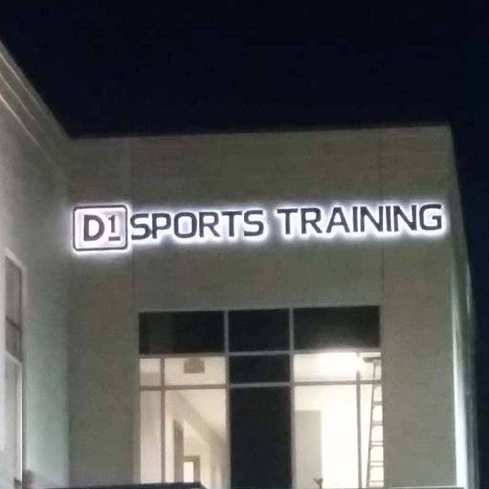 Illuminated sign for D1 Sports Training on a building at night.