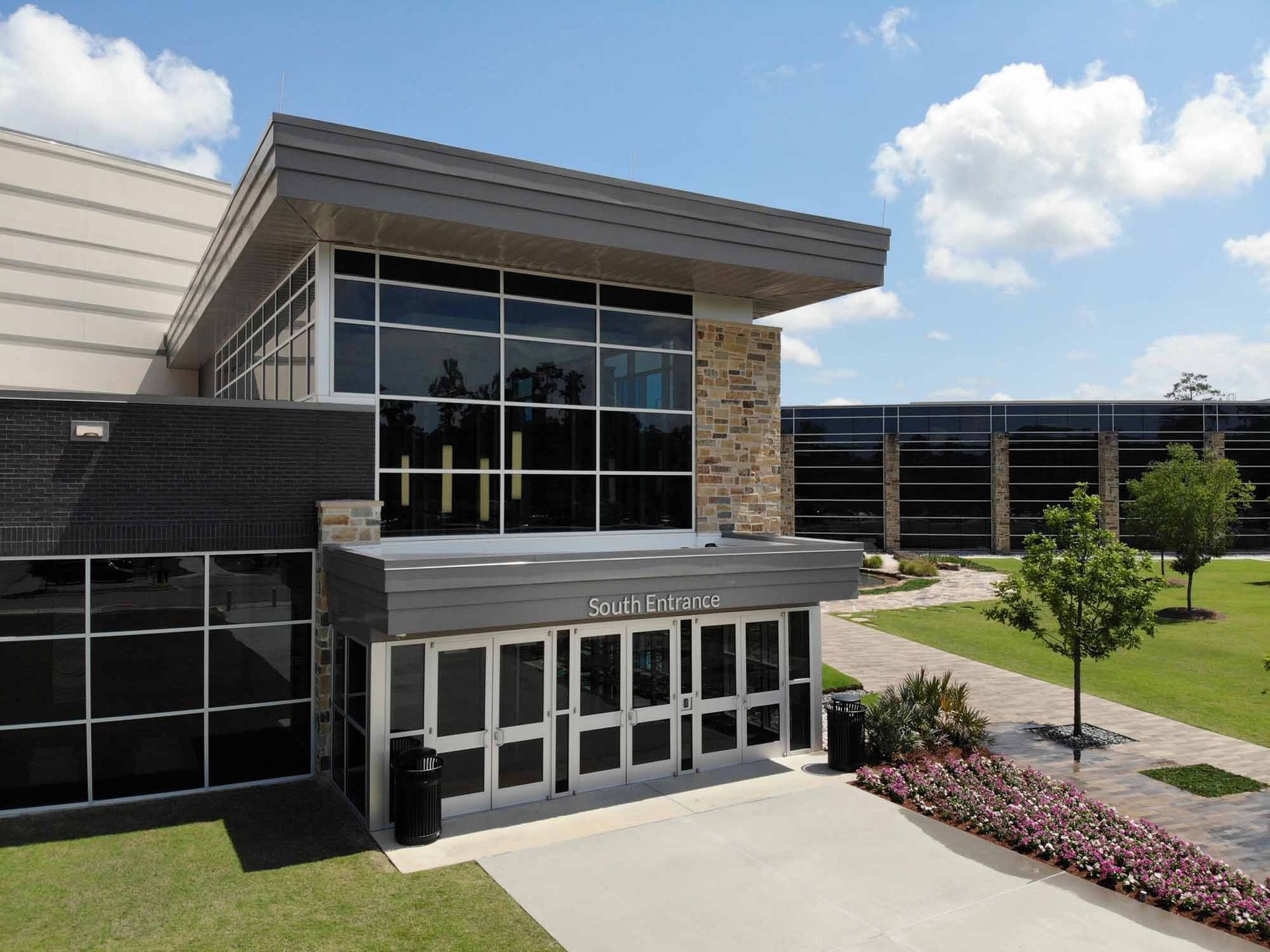 Modern building exterior with glass windows, brick accents, and entrance under a small overhang.