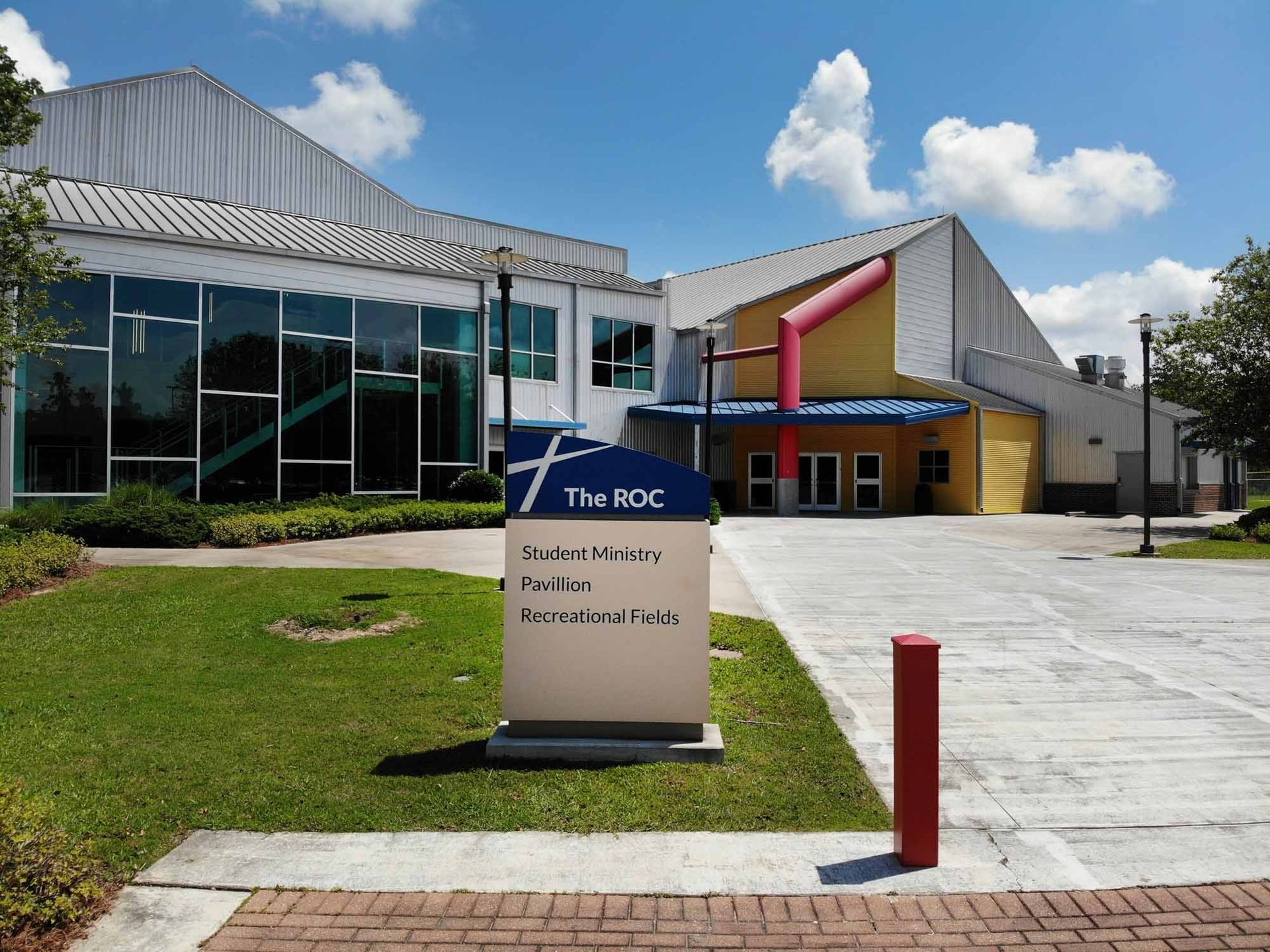 The RDC Community Center, building with sign, blue, white, and yellow exterior. Sunny day.