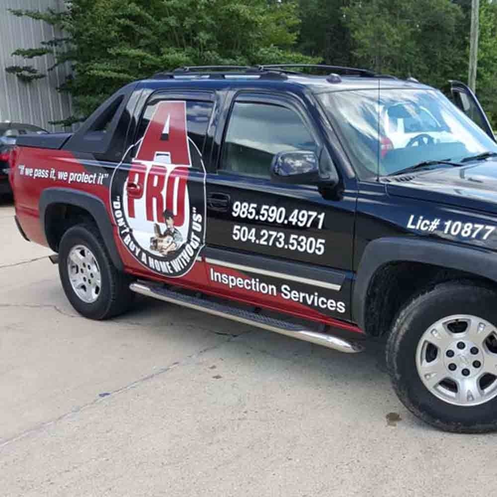Black and red A Pro Inspection Services truck parked, with company logo and contact info on the side.