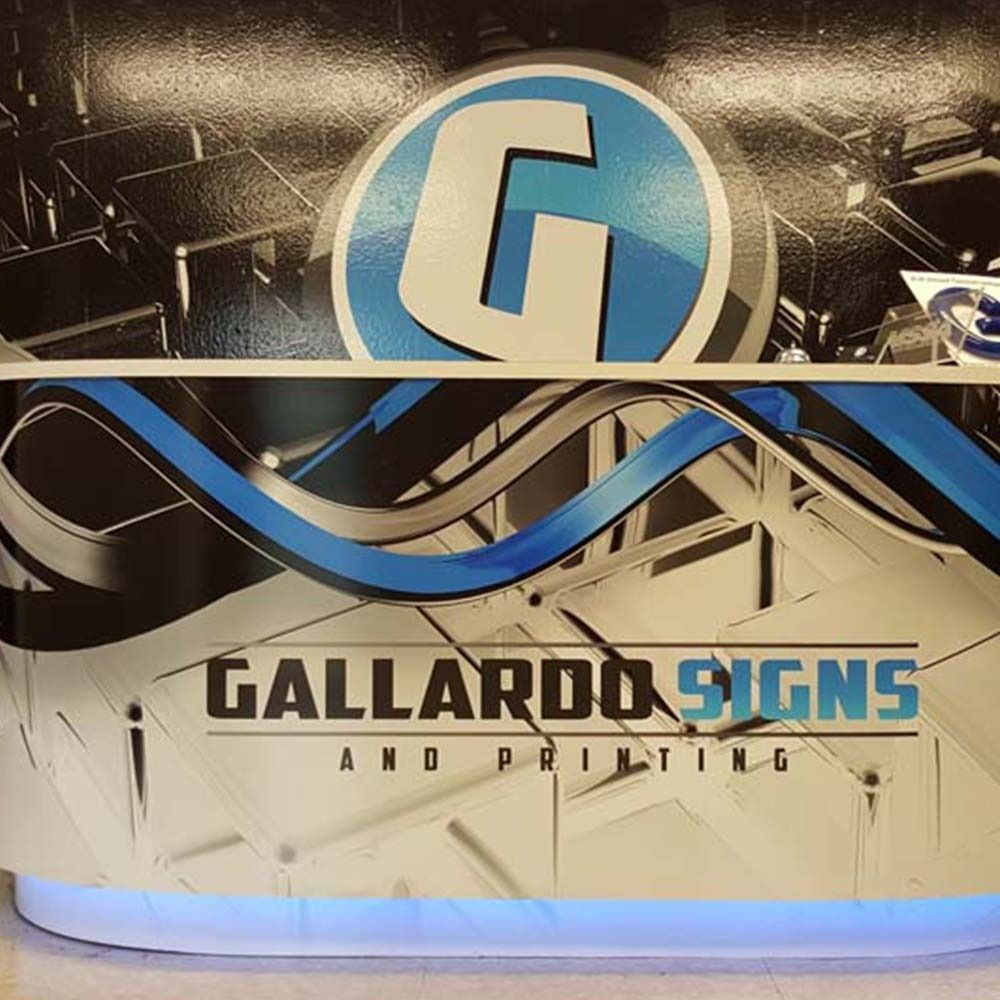 Reception desk with Gallardo Signs logo and blue and black design.