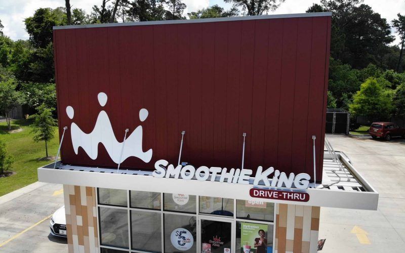 Smoothie King building with a large red facade, white logo, and drive-thru.
