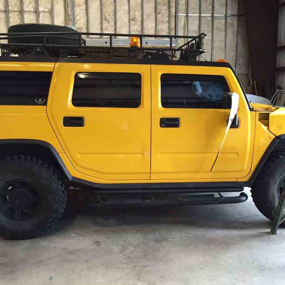 Yellow Hummer SUV with black accents, roof rack, and black tires. Inside a garage.