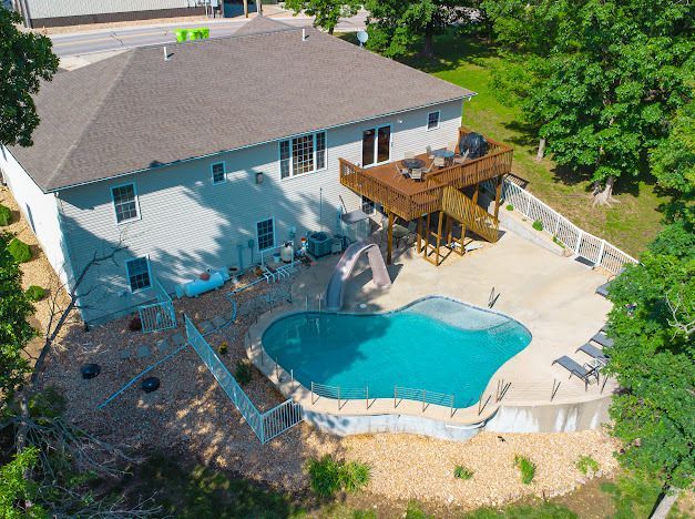 An aerial view of a house with a large swimming pool in the backyard.