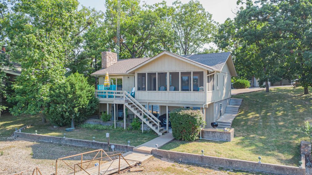 An aerial view of a house sitting on top of a hill next to a body of water.